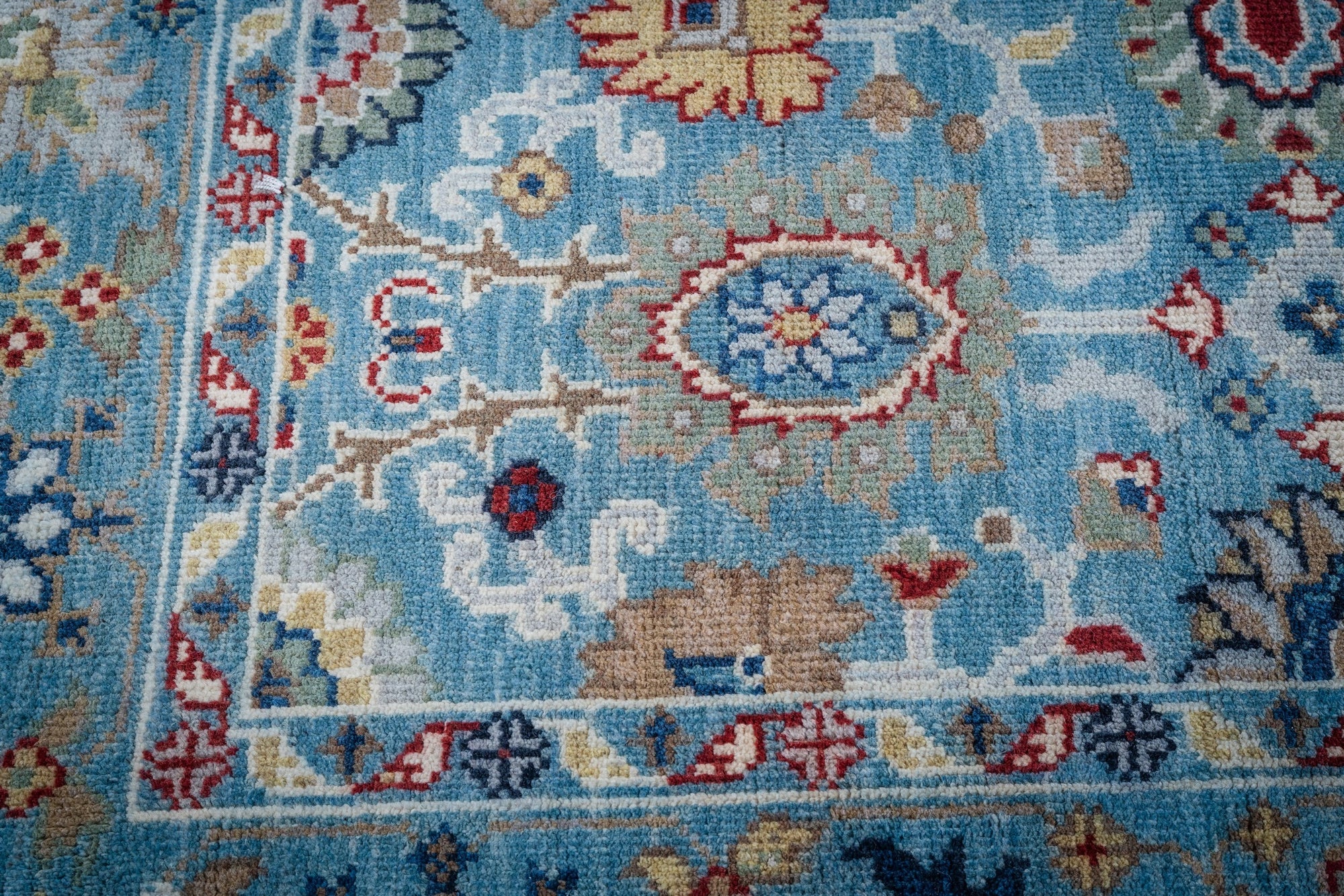 Turquoise Oushak rug corner and floral border detail